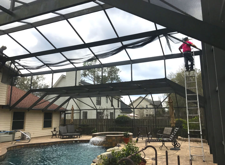Pool screen enclosure being repaired by two men in a backyard near Fleming Island, FL